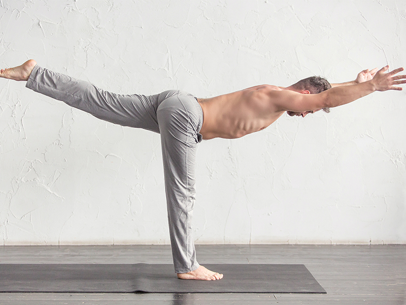 Ein Mann macht die Yoga-Übung Krieger 3.