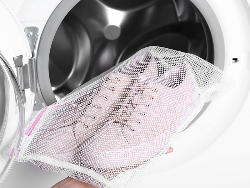 Packe die Schuhe in einen Kissenbezug (oder Waschbeutel). Lege zusätzlich z. B. Handtücher oder Bettwäsche in die Maschine, damit die Schuhe in der Trommel nicht zu sehr herumfliegen.