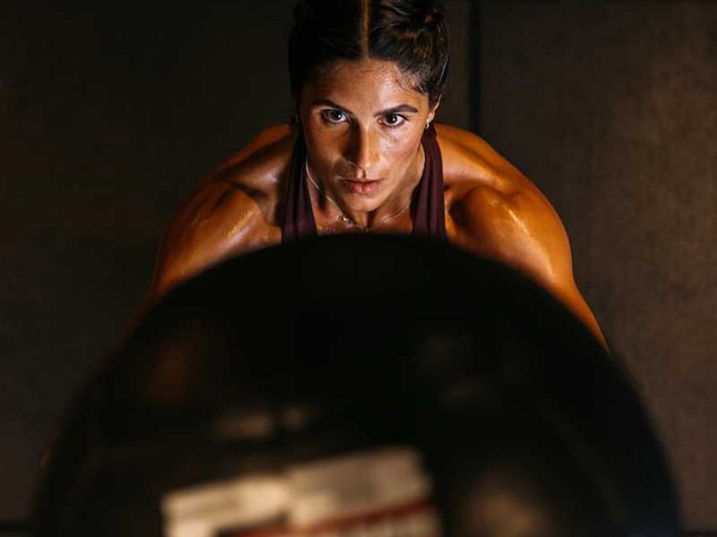 Gehe in die Kniebeuge und wirf‘ den Wallball beim Hochkommen gegen die Wand.