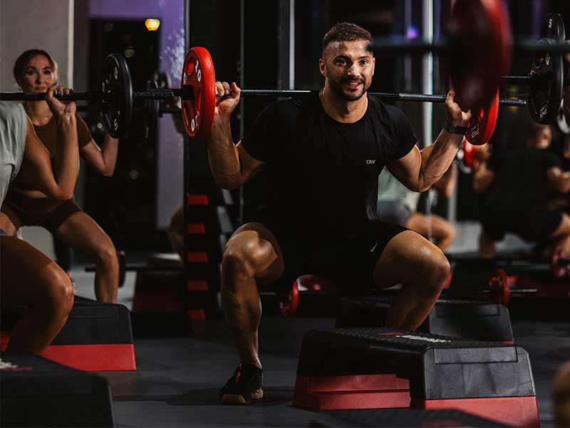 Beim Back Squat liegt eine Langhantel unterhalb deines Nackens auf deinen Schultern, genauer auf dem Trapez-Muskel leicht oberhalb deiner Schulterblätter.