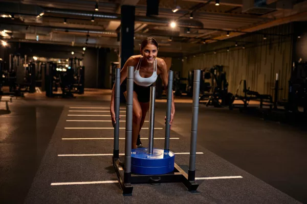 Junge Frau schiebt Gewichtsschlitten.